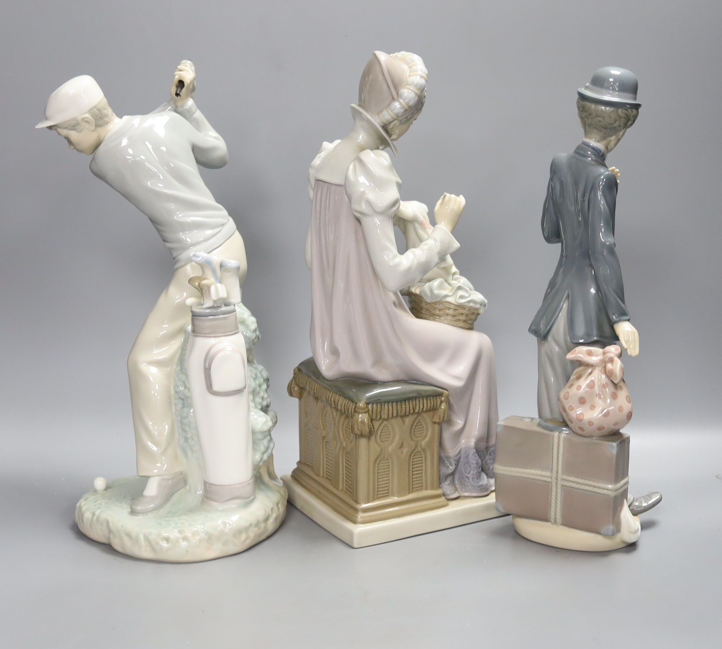 Three Lladro figures: a golfer, Charlie Chaplin and a lady sewing, tallest 28cm